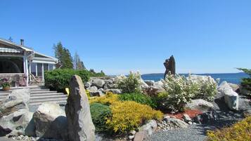Une propriété située sur la côte, agrémentée d’une sculpture en pierre, d’une terrasse avec mobilier d’extérieur et offrant une vue sur la mer.