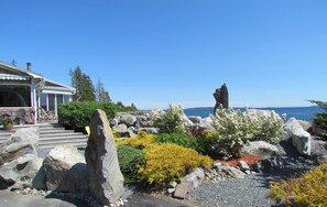 A coastal property with a stone sculpture, a patio with outdoor furniture, and a view of the sea. - OCEAN SURF COTTAGE AT SUMMERVILLE BEACH (Summerville Centre)