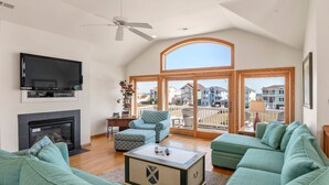 Una sala de estar con chimenea, televisor, ventana grande y un conjunto de sofá verde.