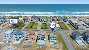 Zona residencial costera con casas, un letrero que indica acceso a la playa y el logotipo de Village Realty.