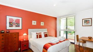 A hotel room with a large bed, a desk, a chair, a dresser, and artwork on the walls. - Stylish River Boulevard Apartment in Richmond (Richmond)