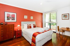 A hotel room with a large bed, a desk, a chair, a dresser, and artwork on the walls. - Stylish River Boulevard Apartment in Richmond (Richmond)