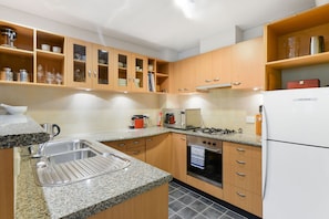 A modern kitchen with granite countertops, stainless steel appliances, and wooden cabinetry. - Stylish River Boulevard Apartment in Richmond (Richmond)