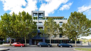 A modern multi-story building with a flat roof, large windows, and a balcony on the upper floor. - Stylish River Boulevard Apartment in Richmond (Richmond)