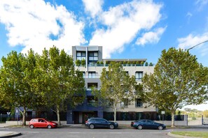 A modern multi-story building with a flat roof, large windows, and a balcony on the upper floor. - Stylish River Boulevard Apartment in Richmond (Richmond)