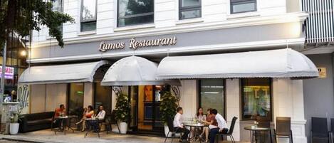 A restaurant named 'Lumos Restaurant' with outdoor seating and a white awning.
