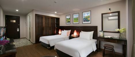 A hotel room with two beds, a desk, a chair, a coffee table, and a bookshelf.