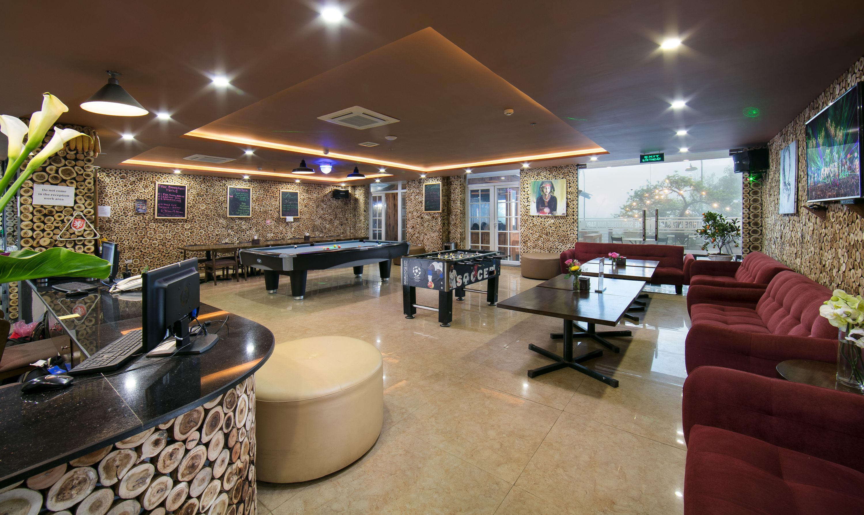 A billiards room with pool tables, a foosball table, and a bar area with a counter and seating.