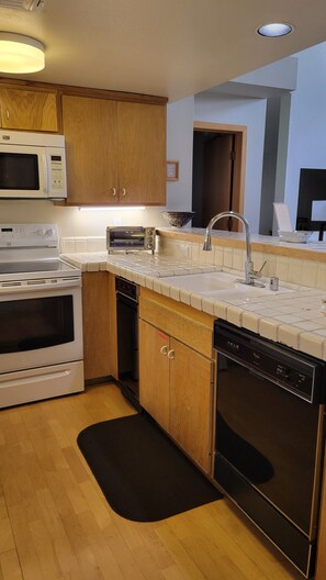 A modern kitchen with wooden cabinets, a microwave, stove, dishwasher, and a sink with a faucet.