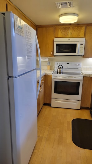 A kitchen with a refrigerator, microwave, stove, and oven.