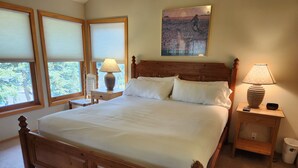 A neatly made bed with a wooden headboard, two bedside tables with lamps, and a painting on the wall. - Snowcreek Resort Vacation Rental 858 (Mammoth Lakes)
