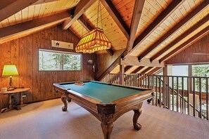 Une table de billard dans une pièce aux murs en bois et au plafond en pente.