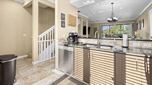 A modern kitchen with a central island, stainless steel appliances, and a view to the outside. - Cedars East #528 Townhome by RVA (Longboat Key)