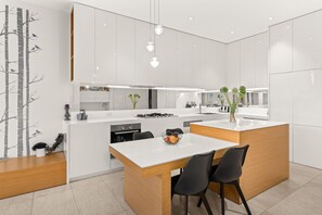 A modern kitchen with a central island, black chairs, and a dining table. - The Residence Pet Friendly Retreat Dendy Victoria (Brighton)