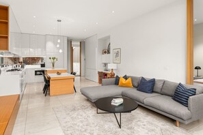 A modern living space with a kitchen, dining area, and a grey sofa with cushions. - The Residence Pet Friendly Retreat Dendy Victoria (Brighton)