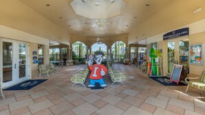 A covered outdoor area with a ceiling fan, lounge chairs, and a mascot statue.
