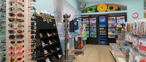 A store with sunglasses on display, a refrigerated section, and various items on shelves.