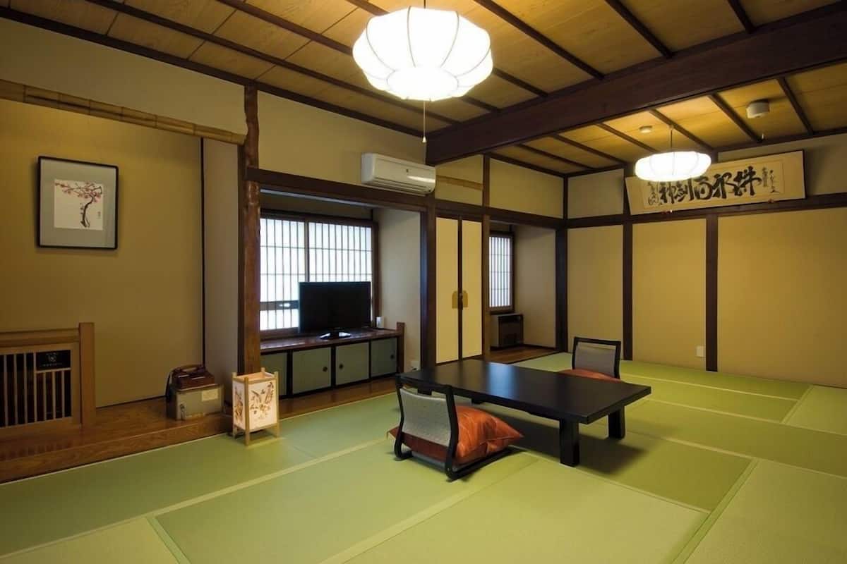 A traditional Japanese room with tatami flooring, a low table, a television, and sliding doors.