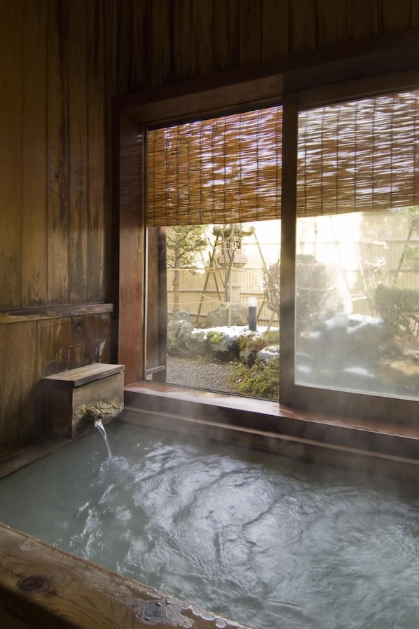 A traditional wooden bath with a view of a garden.