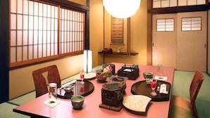 Una habitación japonesa tradicional con suelo de tatami, una mesa baja con un juego de té y puertas correderas.