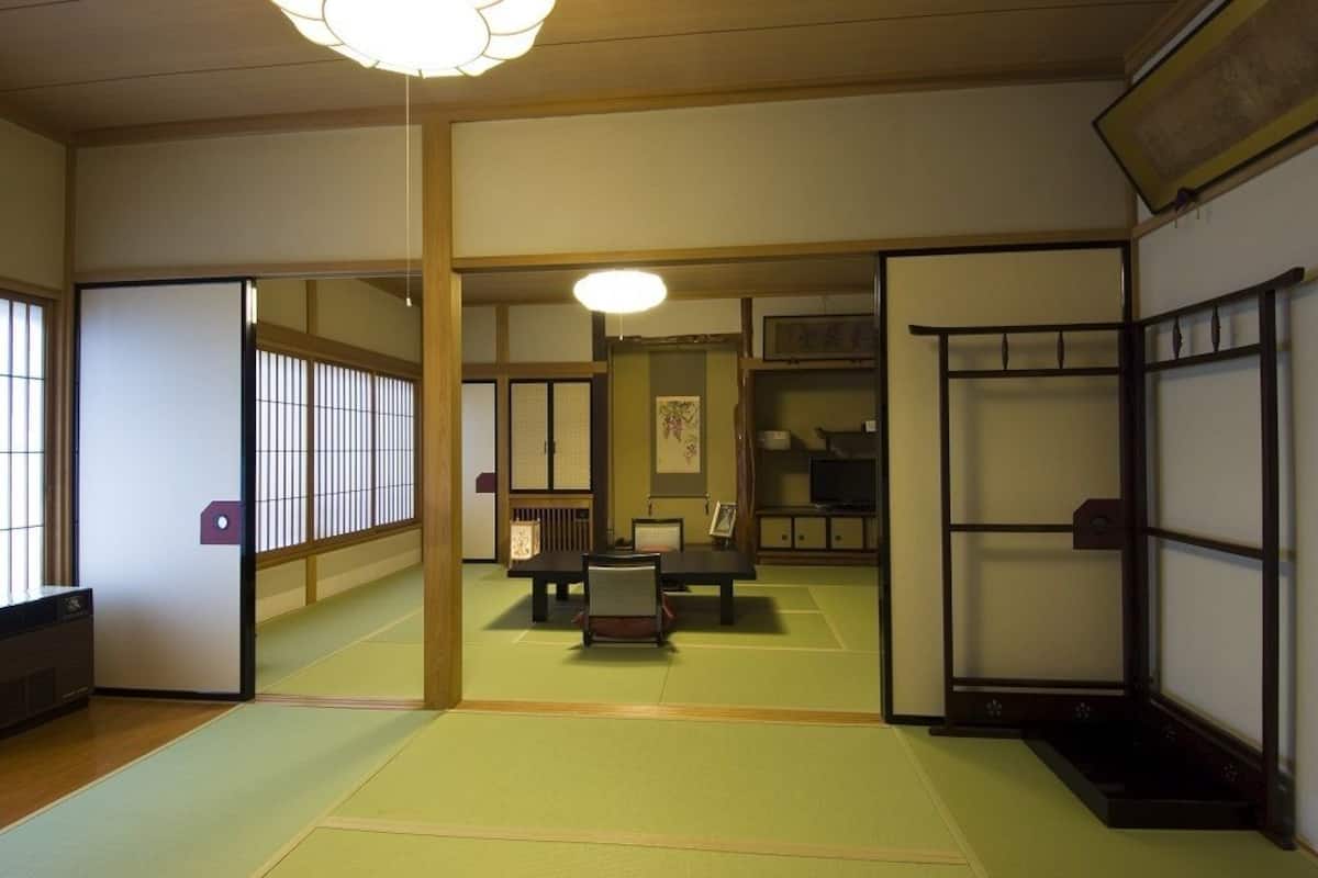 A traditional Japanese room with tatami flooring, a low table with a chair, and sliding doors.