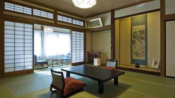 Um quarto japonês tradicional com tatames, uma mesa baixa e uma cadeira acolchoada.