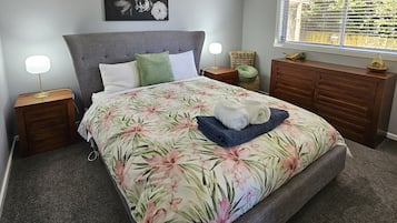 Una camera da letto con un letto, comodini, una cassettiera, una finestra con tende e un condizionatore d'aria a parete.