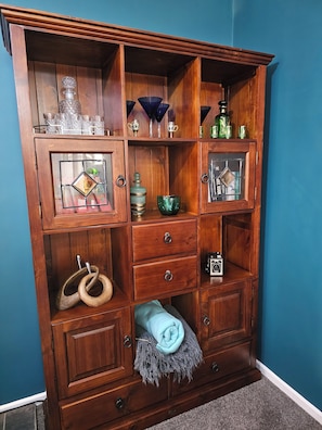 A wooden cabinet with multiple compartments, some containing glassware and decorative items.