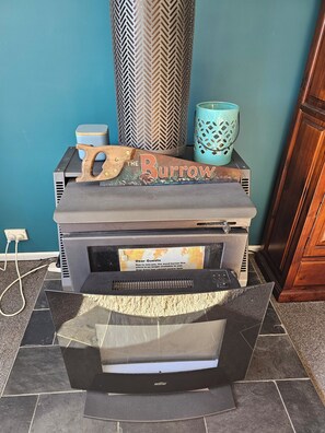 A wood-burning stove with a sign reading 'The Burrow' and a decorative wooden piece on top.