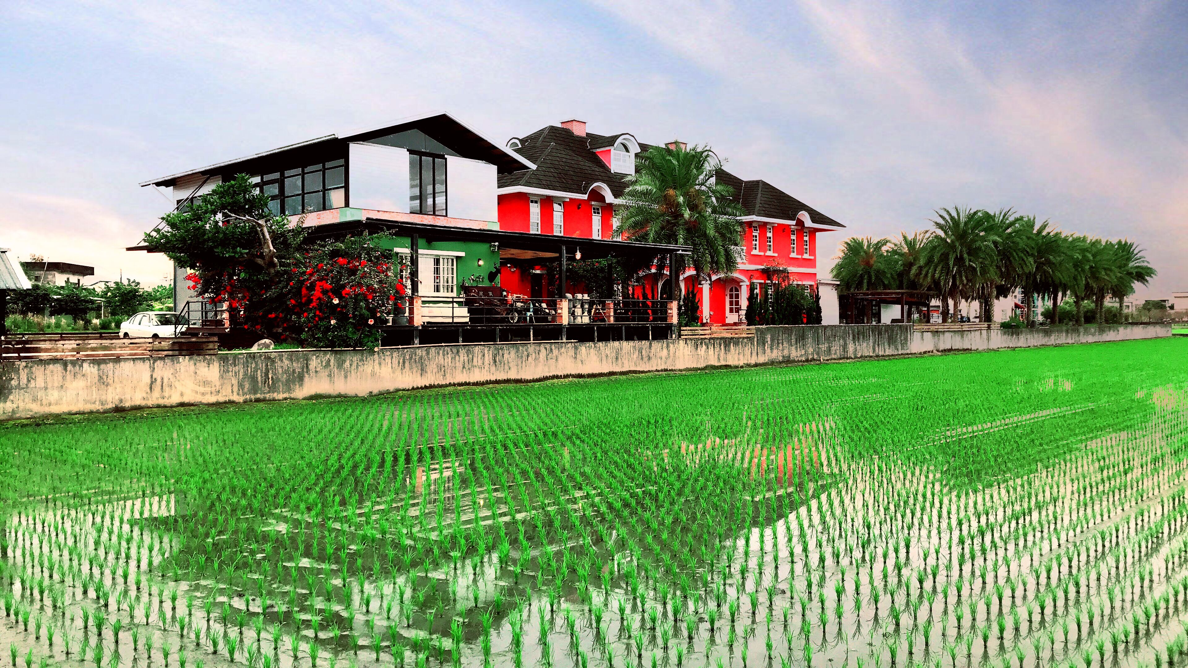 A two-story house with a balcony, adjacent to a well-maintained green field.