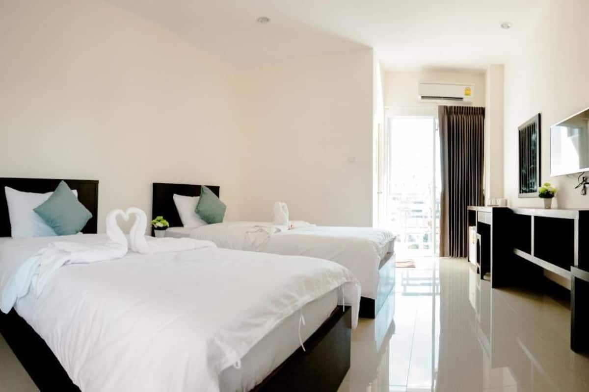 Una habitación de hotel con dos camas, un escritorio y un ventanal grande.