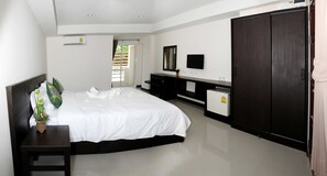 A bedroom with a large bed, a dresser, a TV, and a wardrobe. - Won Place (Khon Kaen)