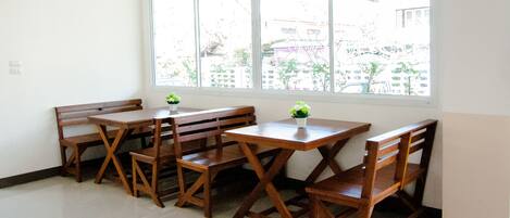 Una habitación con un ventanal grande, muebles de madera y una planta pequeña.