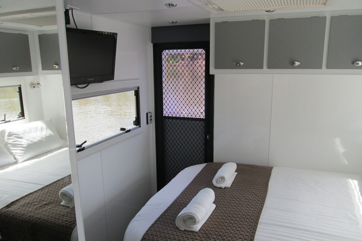 A hotel room with a bed, a TV, a window, and a door.
