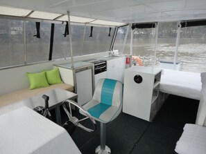 Een compact verblijf met een kleine kitchenette, een zithoek met kussens en uitzicht op het water door de ramen.