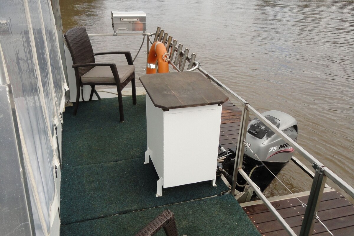 A deck area with a table, chairs, a small white cabinet, and a water motor.