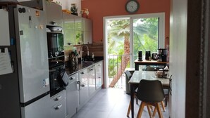 Une cuisine avec des meubles blancs, un réfrigérateur, une cuisinière et un coin repas comprenant une table et des chaises.
