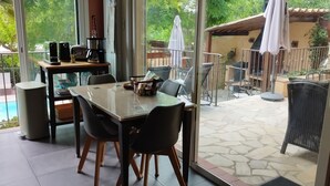 Un espace patio aménagé avec une table en verre, des chaises, un coin café et du mobilier d’extérieur.