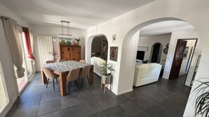 Un grand espace de vie comprenant une table à manger, un canapé et une cuisine en arrière-plan.