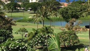 A golf course with a large building in the background, palm trees, and a view of the ocean. - Ocean & golf views , watch amazing sunsets over Lana'i- J301 2/2 Sleep up to 7 (Lahaina)