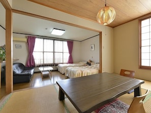 A traditional Japanese-style room with tatami flooring, a low wooden table, and a sofa. - Yumoto Miyoshi (Beppu)