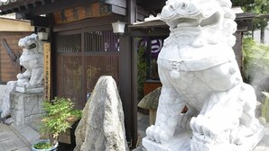 Un edificio japonés tradicional con una entrada de madera y dos estatuas de leones.