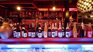 Un bar con una variedad de botellas y un candelabro decorativo colgante.