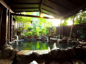 A traditional Japanese garden with a koi pond, rocks, and a wooden structure. - Yumoto Miyoshi (Beppu)