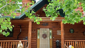 En stuga av trä med en inbjudande skylt, en dörr prydd med en krans och en staty på verandan.