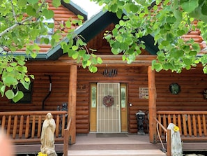 A wooden cabin with a welcoming sign, a door with a wreath, and a statue on the porch.