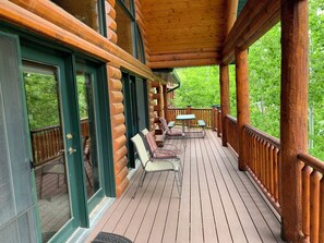 Una terraza de madera con mobiliario exterior y un área techada.