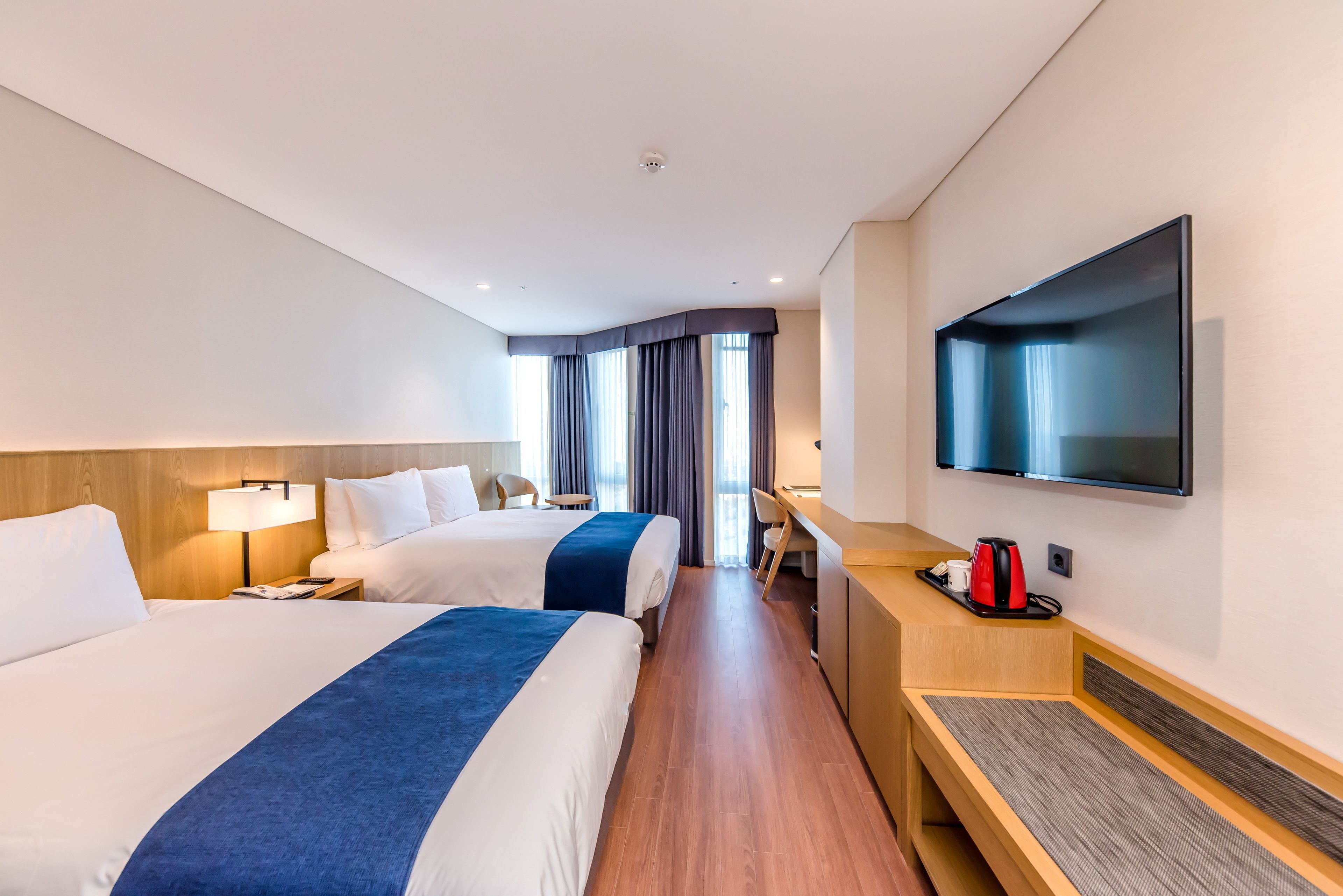 Ein Hotelzimmer mit zwei Betten, einem Schreibtisch, einem Fernseher und einer Kaffeemaschine.