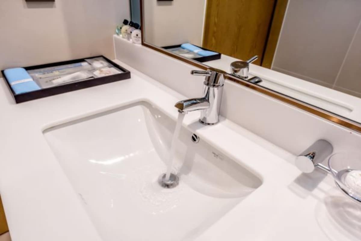 A modern bathroom with a white sink, chrome faucet, and a glass soap dish.