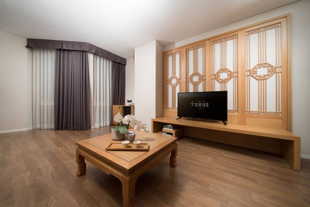 Una sala moderna con una mesa de centro de madera, un televisor de pantalla plana y un panel de pared de estilo asiático tradicional.
